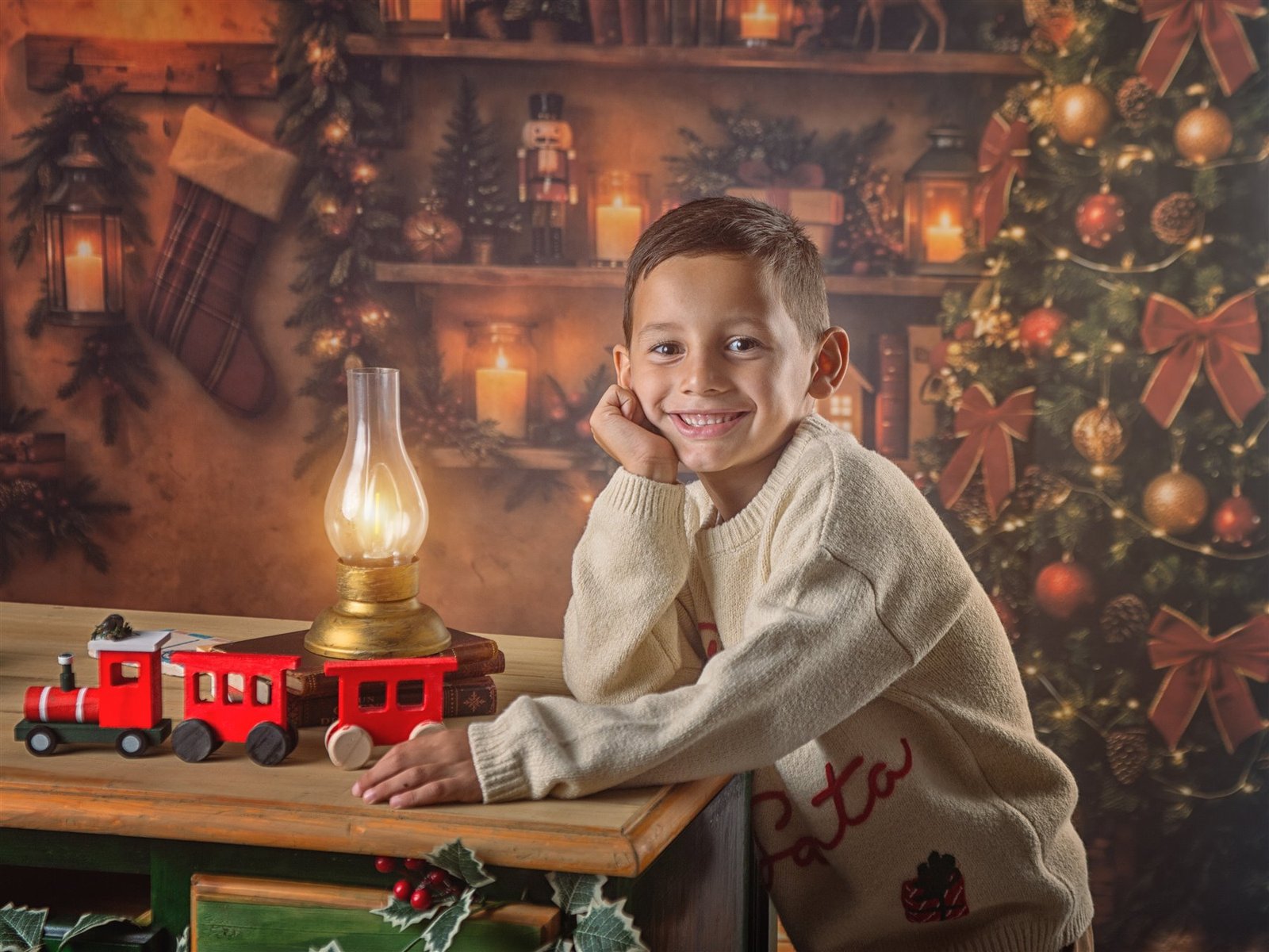 Niño sonriendo junto a un tren de juguete en el Taller de Sueños